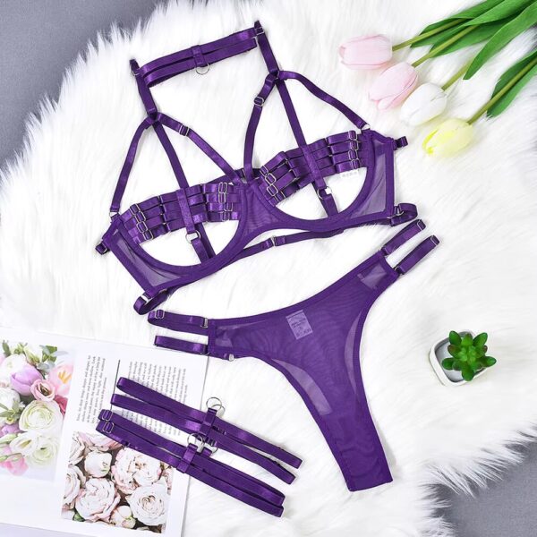 Purple semi-transparent lingerie set displayed on a bed, featuring a bra, thong, garter belt, and collar, highlighting the daring and seductive style.