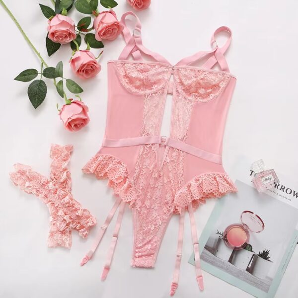 Full view of the pink bodysuit and garter set displayed on a bed, showcasing the romantic and delicate design.