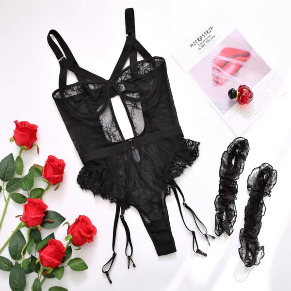 Full view of the black bodysuit and garter set displayed on a bed, featuring delicate frills and a romantic design.