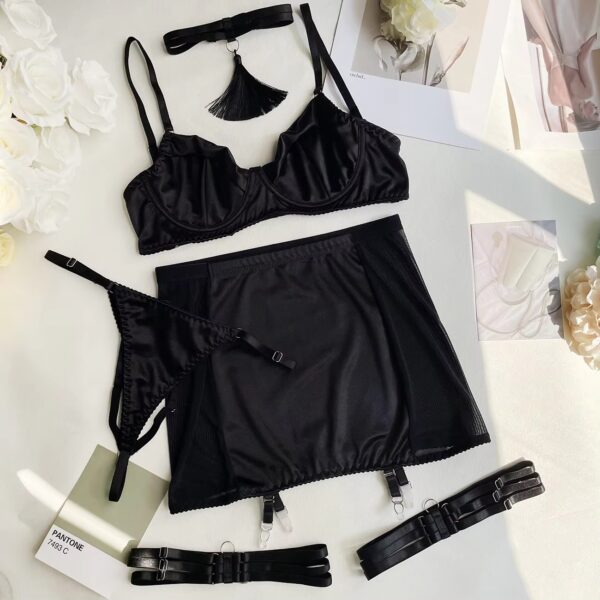 Black lingerie set displayed on a bed, including a bra, thong, skirt, garters, and collar, showcasing its sensual and mysterious design.